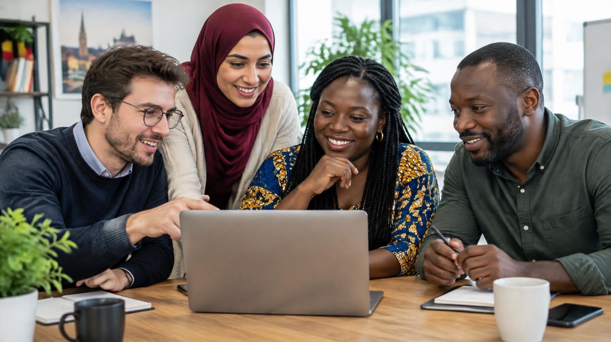 Colleagues collaborating around a laptop in an office